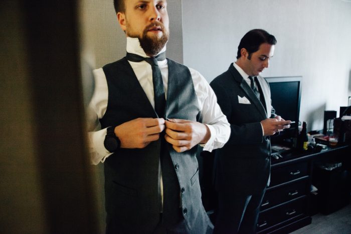 Groom Buttoning Up Vest with Groomsmen 