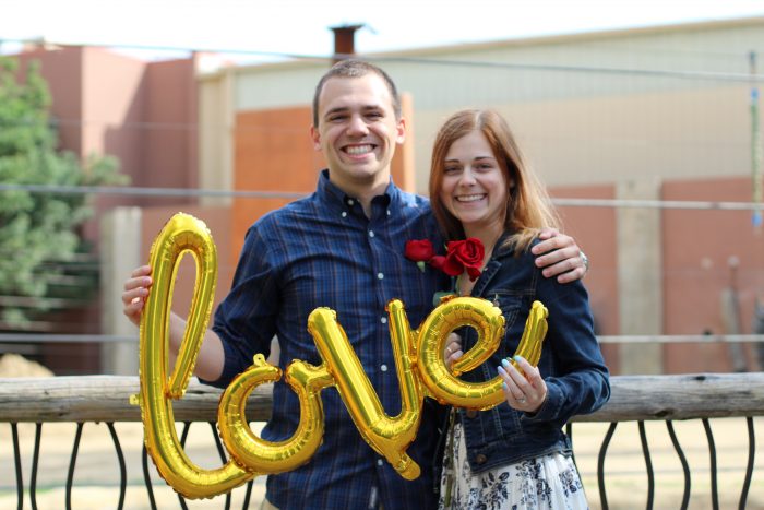 Fiance with His Fiancee Holding Up Balloons that Spell Love After Getting Engaged