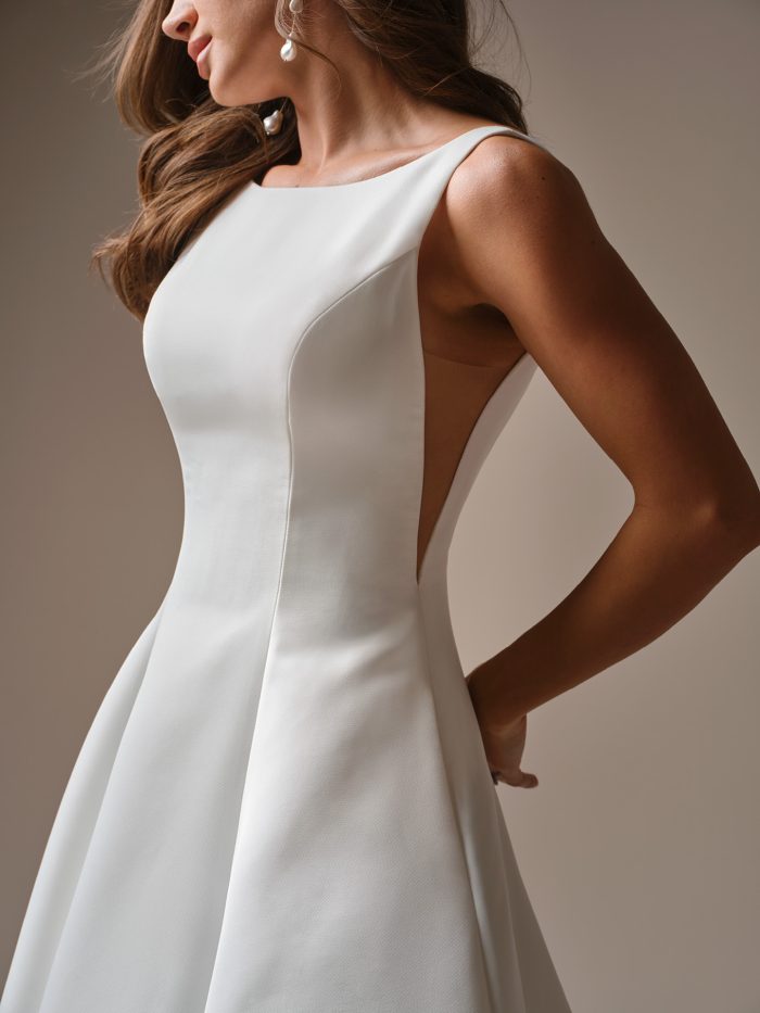 Close-up of minimalist satin wedding dress with bateau neckline, sleek bodice, and wide tank straps.