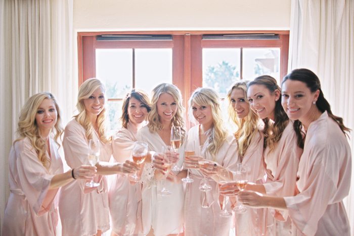 Bride Standing with Bridesmaids Cheering with Champagne Flutes