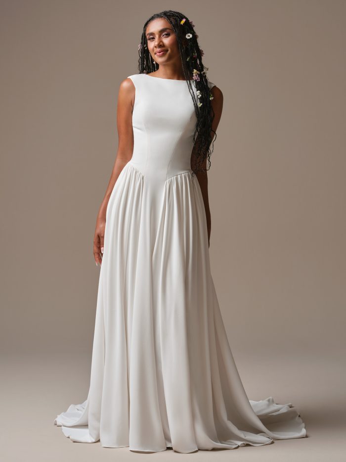 Minimalist A-line wedding dress with bateau neckline, cap sleeves, and soft flowing crepe skirt.