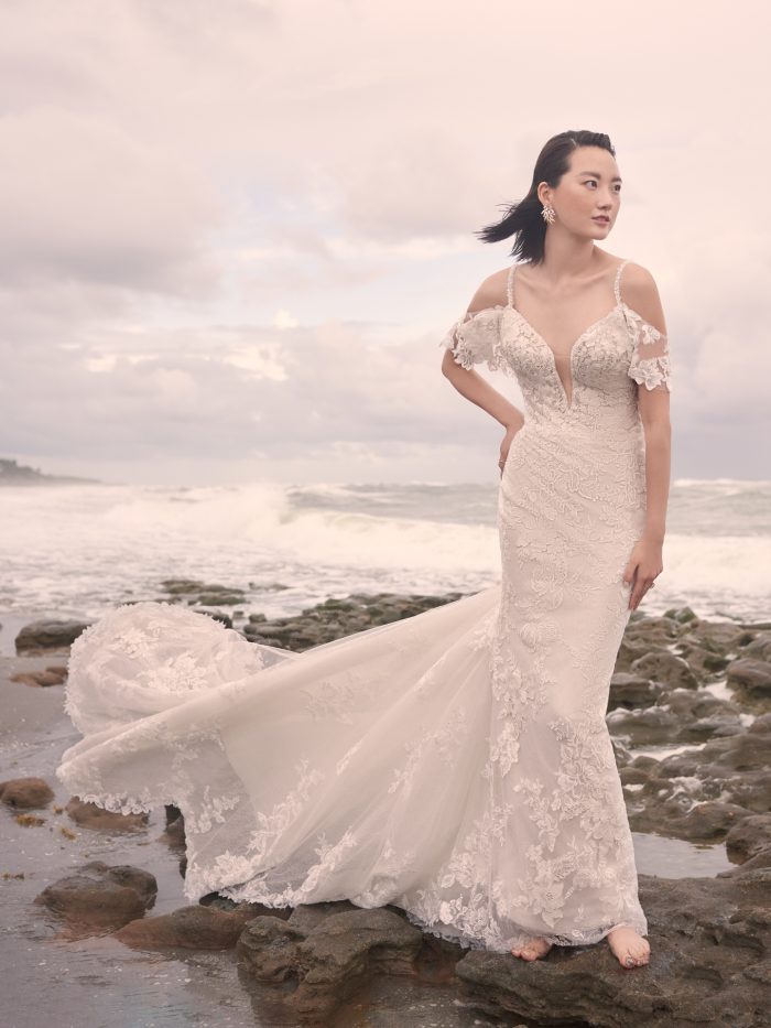Model on Beach Wearing Lace Mermaid Wedding Dress with Long Train Called Bryan by Sottero and Midgley