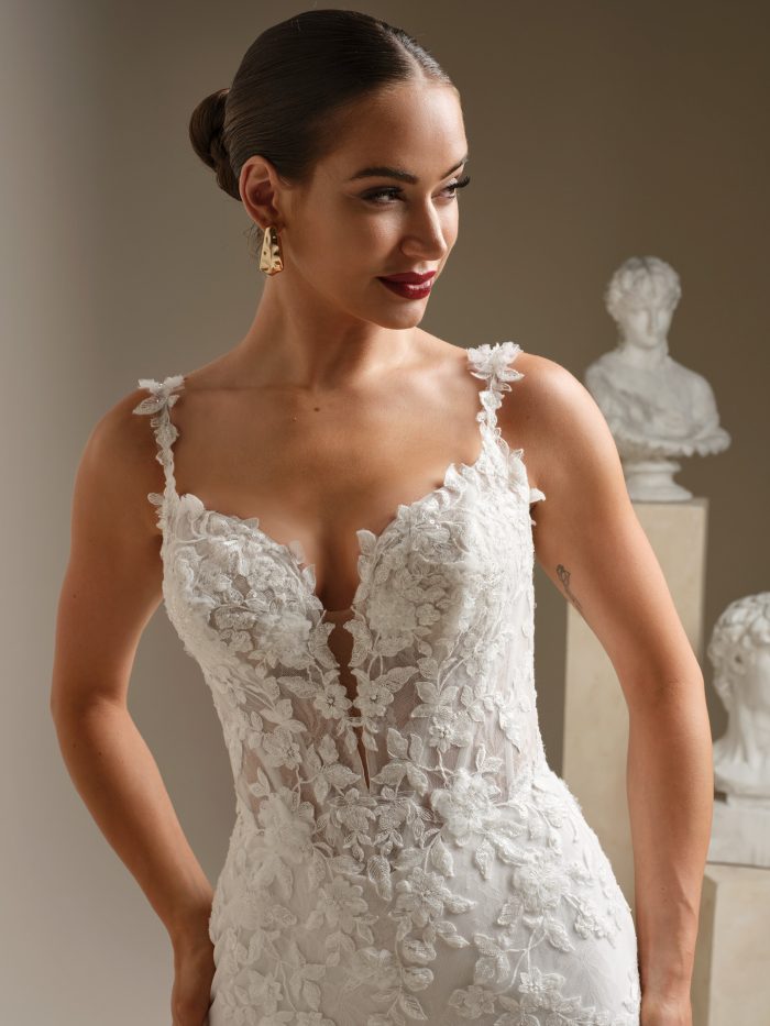 Close-up of lace fit-and-flare wedding dress bodice with illusion plunge neckline, delicate floral lace appliqués, and thin straps.