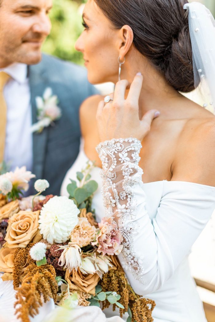 Groom Sitting at Italian Wedding with Bride Wearing Off-the-Shoulder Crepe Wedding Dress Called Admina by Sottero and Midgley