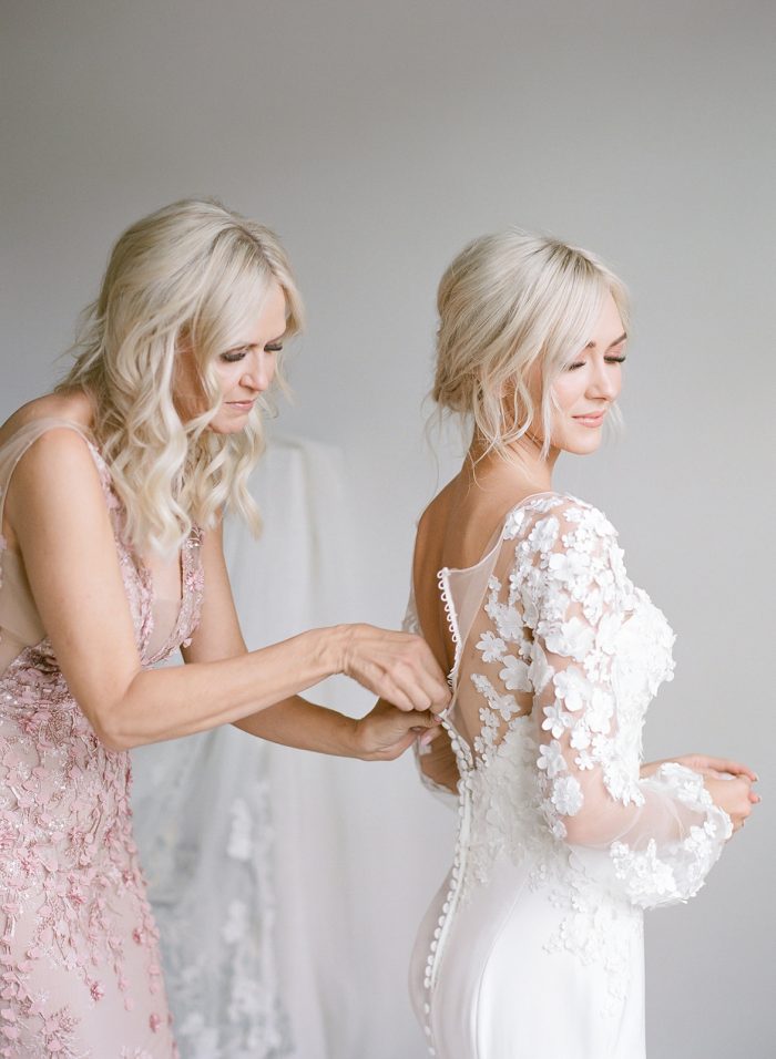 Mother of the Bride Helping Model Ashlee Jensen Wearing Custom Maggie Sottero Wedding Dress with Illusion Lace Floral Bishop Sleeves