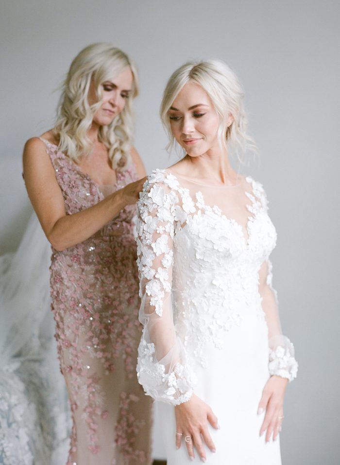 Mother of the Bride Helping Model Ashlee Jensen Wearing Custom Maggie Sottero Wedding Dress with Illusion Lace Floral Bishop Sleeves