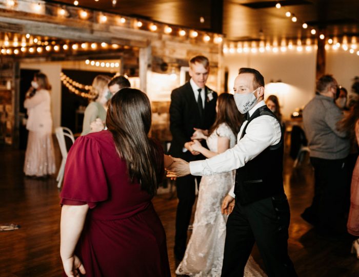 Bride and Groom with Wedding Party Dancing During Rustic Wedding Reception