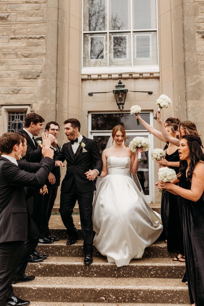 Bride wearing Selena by Maggie Sottero with her friends wearing black bridesmaid dresses