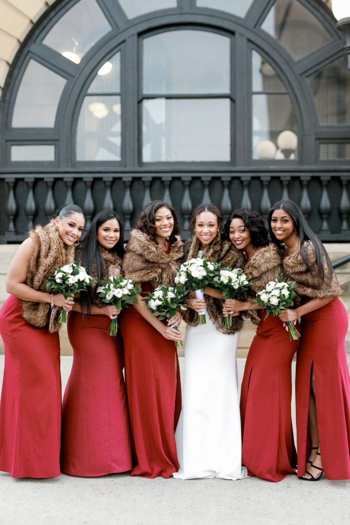 Black Bride Wearing Maggie Sottero Wedding Gown with Bridesmaids Wearing Red Dresses with Shawls for Winter Wedding