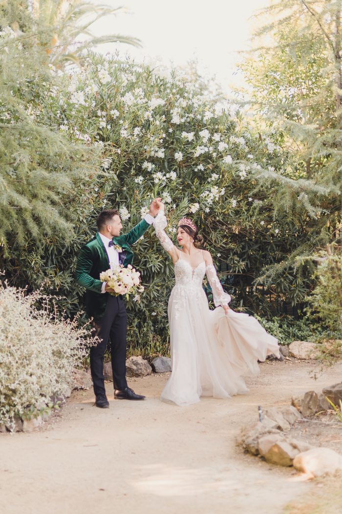 Model Wearing Lace A-line Wedding Dress called Stevie by Maggie Sottero and Groom in a green velvet suit jacket in a garden