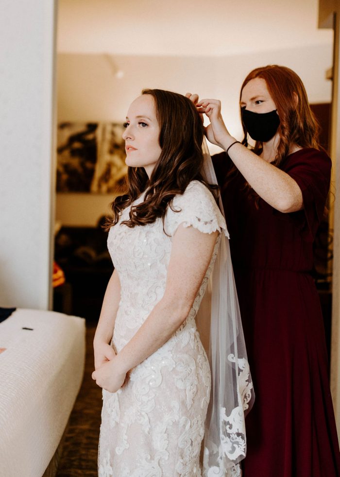 Real Bride wearing Modest Lace Wedding Dress called Tuscany Leigh having her Maid of Honor put on her veil