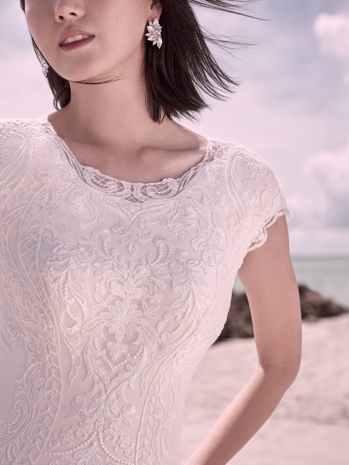 Model wearing Modest Unique lace wedding dress Kevyn Leigh by Sottero and Midgley on the beach