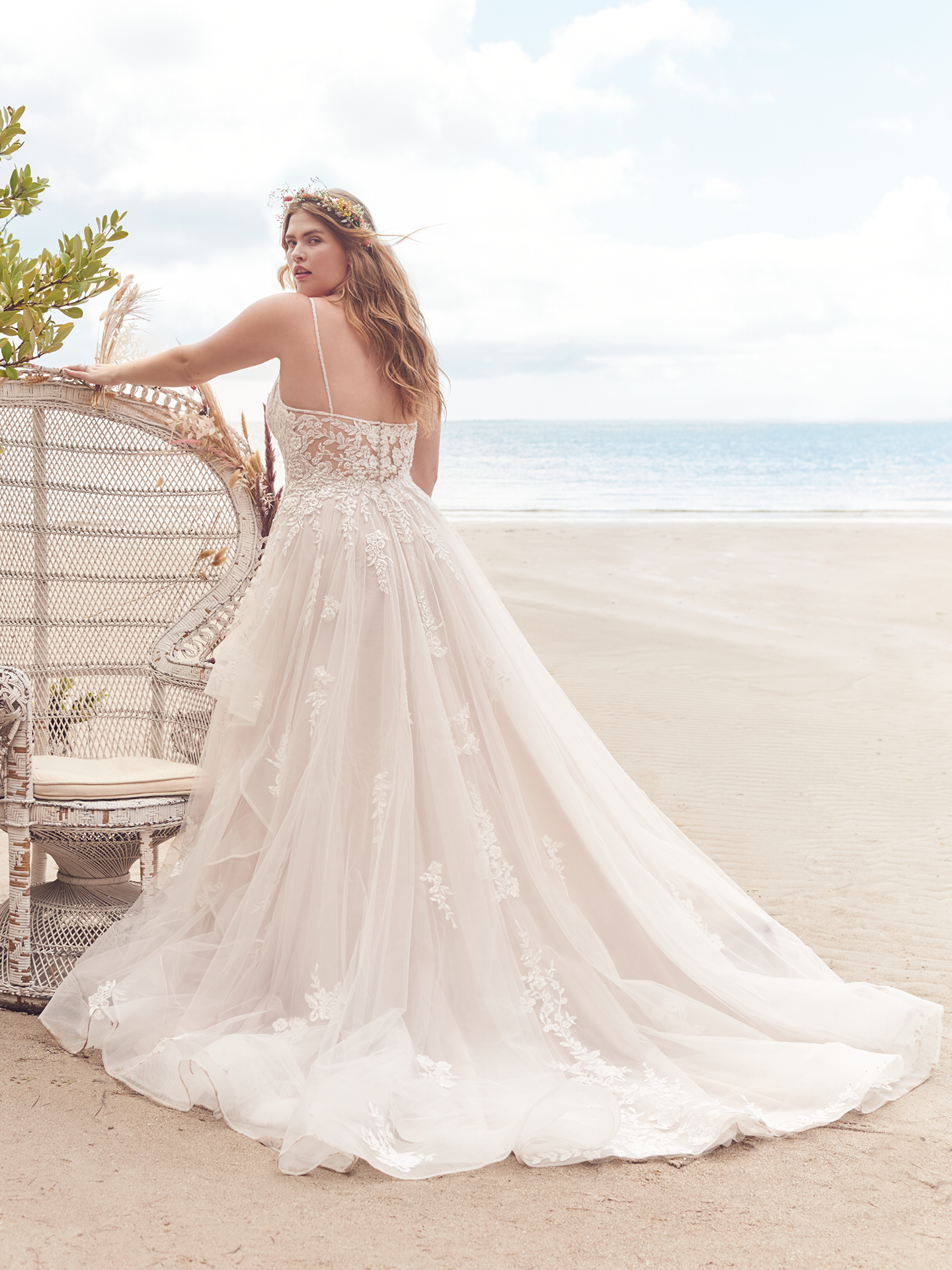 Photo d'une mariée grande taille sur la plage vêtue d'une robe de mariée dos nu appelée Lettie par Rebecca Ingram