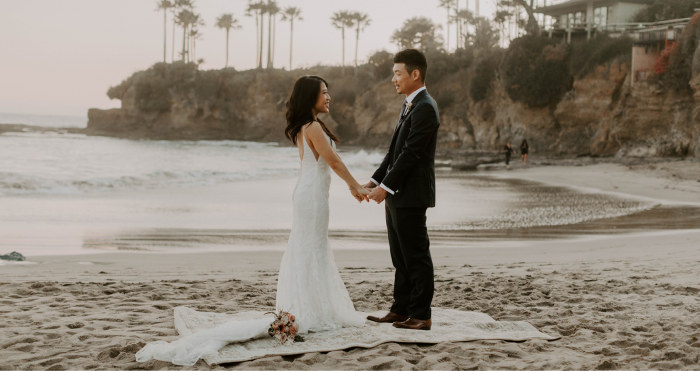 Real Bride and Groom Holding Hands at Intimate and Casual Beaching Wedding While Brides Wearing a Maggie Sottero Wedding Dress
