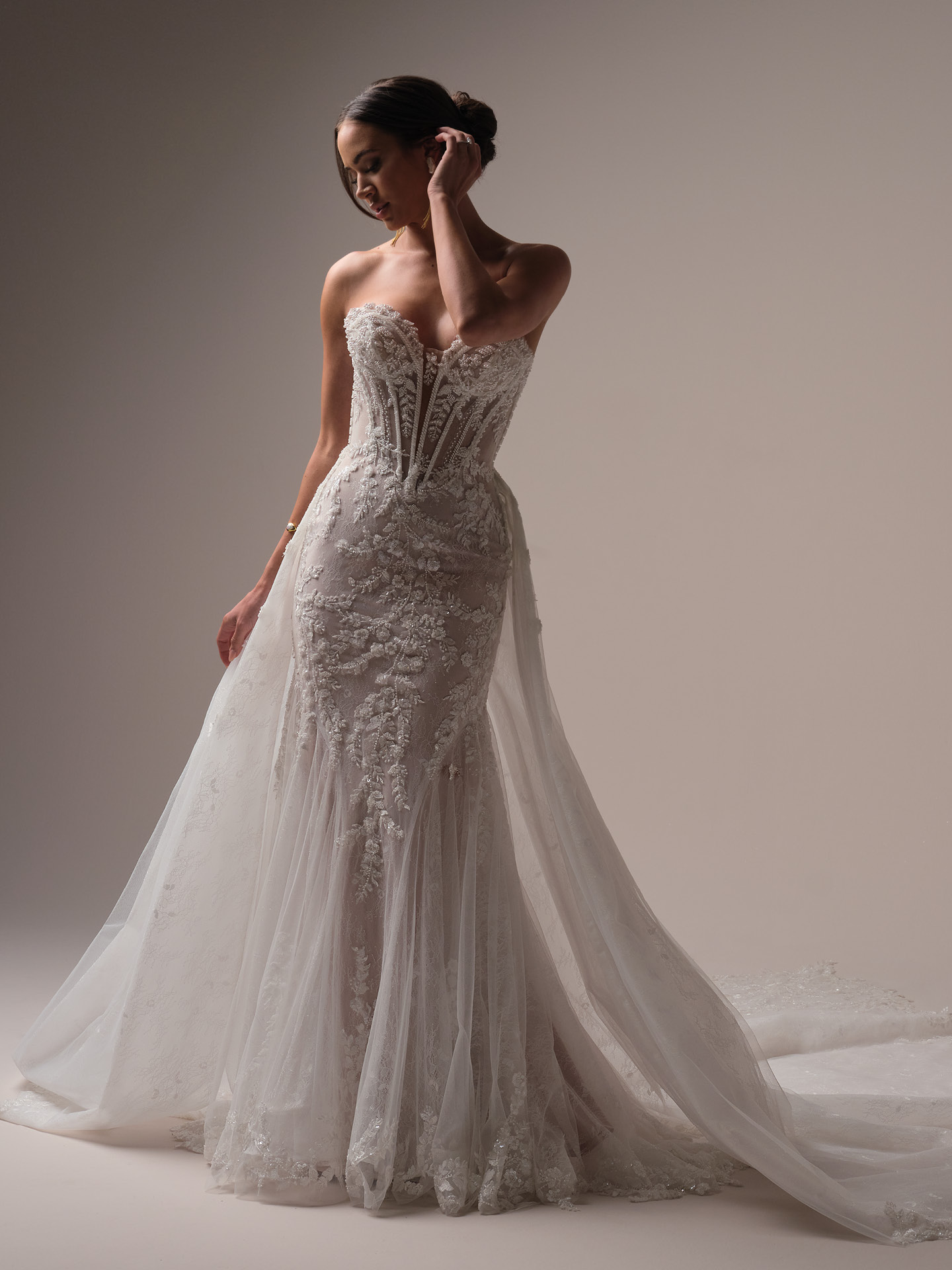 Bride wearing Maggie Sottero Benjie Royale train detachable lace train over a strapless lace wedding dress, full-length view with dramatic overskirt and train.