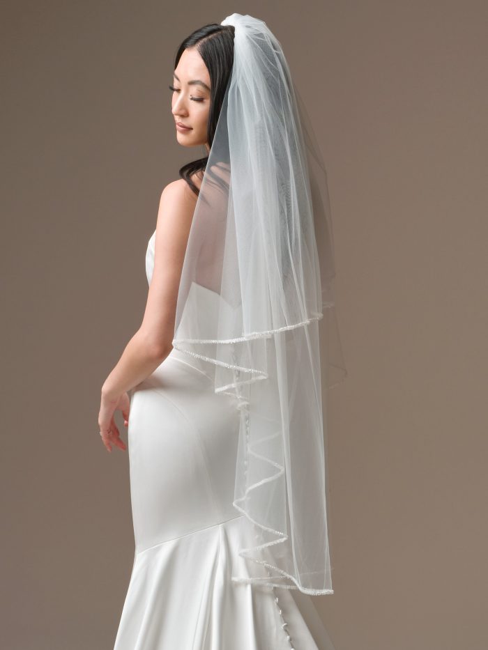 Bride wearing Maggie Sottero Essentials Edit Veil fingertip veil with beaded edge paired with a fitted satin wedding dress, back view.