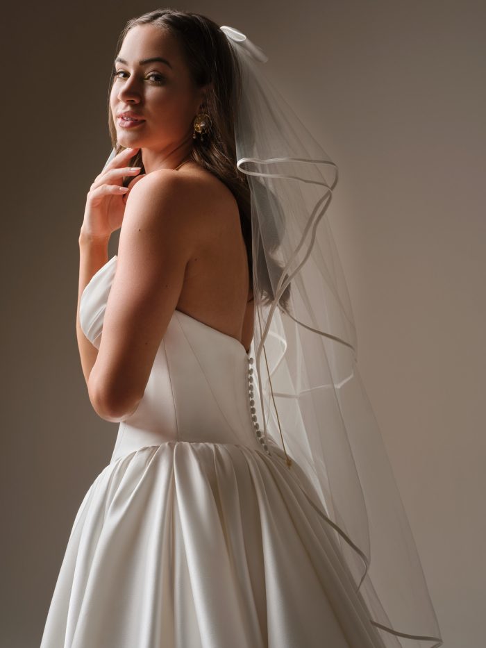 Back view of Maggie Sottero Hudson Fingertip Veil with ribbon trim paired with a strapless satin ballgown wedding dress.