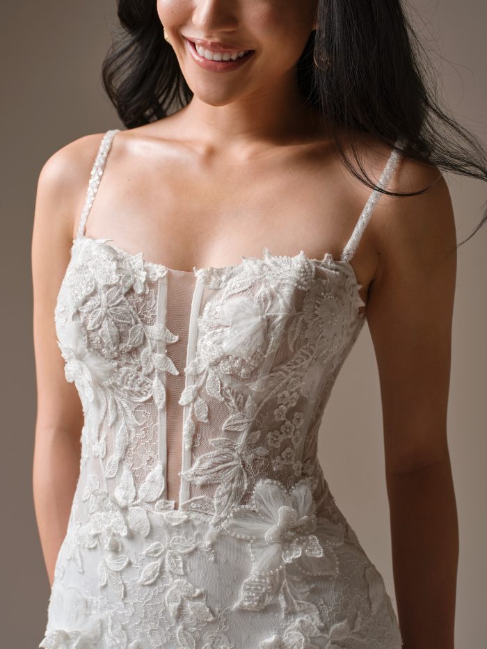 Close-up of Maggie Sottero Laurie fit and flare wedding dress 26MK428A01 strapless lace bodice with floral lace appliqués and beaded spaghetti straps.