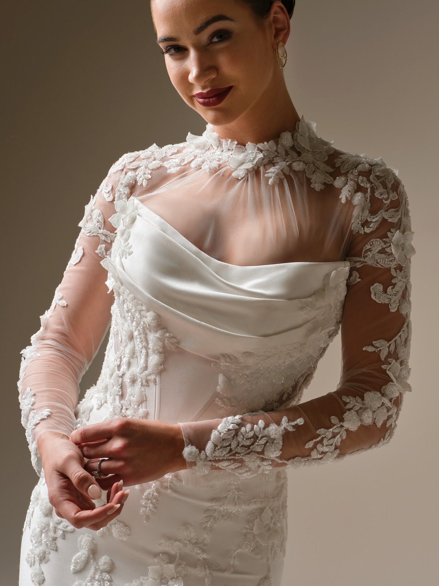 Bride wearing Sottero and Midgley Burke jacket long sleeve illusion lace bridal jacket layered over a strapless wedding dress, close-up view.
