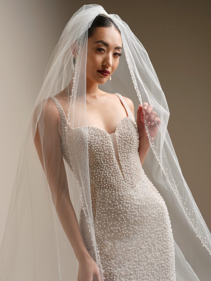 Sottero and Midgley Cooper cathedral veil with pearl edge paired with a pearl beaded strapless fit-and-flare wedding dress, front view.