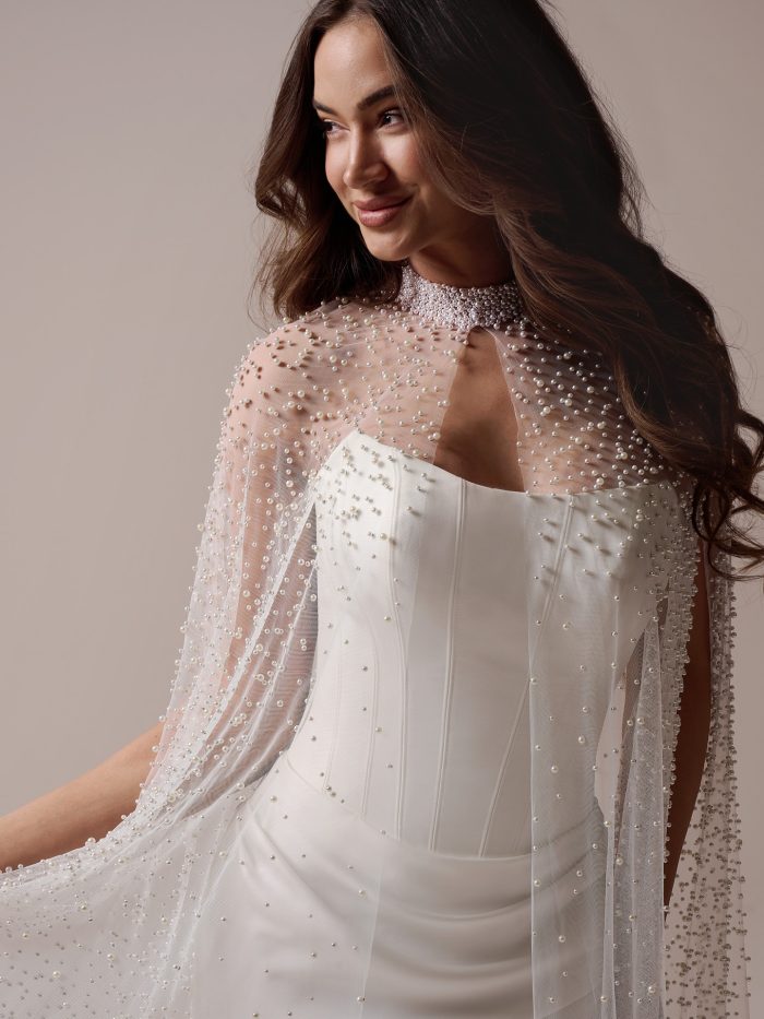 Bride wearing Sottero and Midgley Forsythia cape accessory , a pearl-embellished sheer bridal cape styled over a strapless wedding dress, shown from front and back views with flowing train.