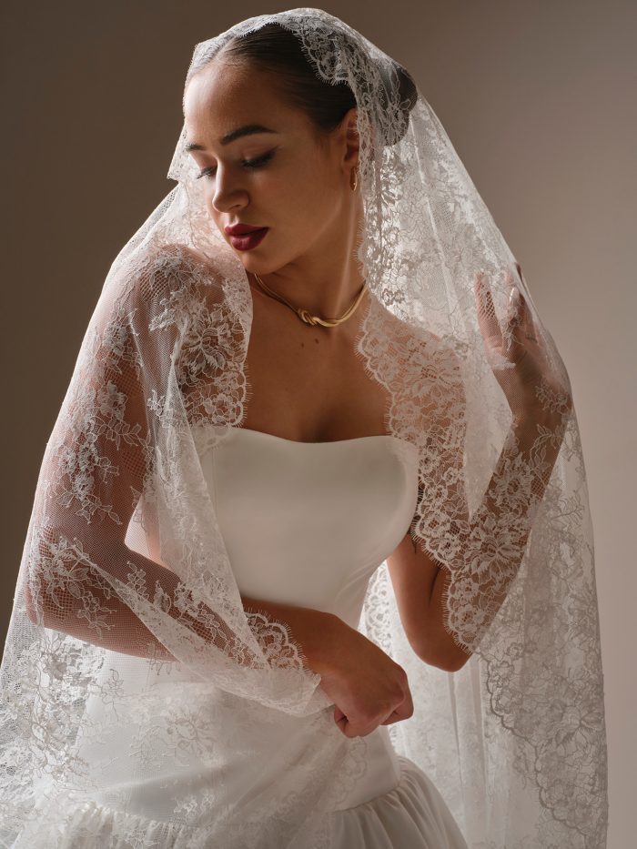 Close-up of Sottero and Midgley Lassen lace cathedral veil draped over a strapless wedding dress with lace detailing.