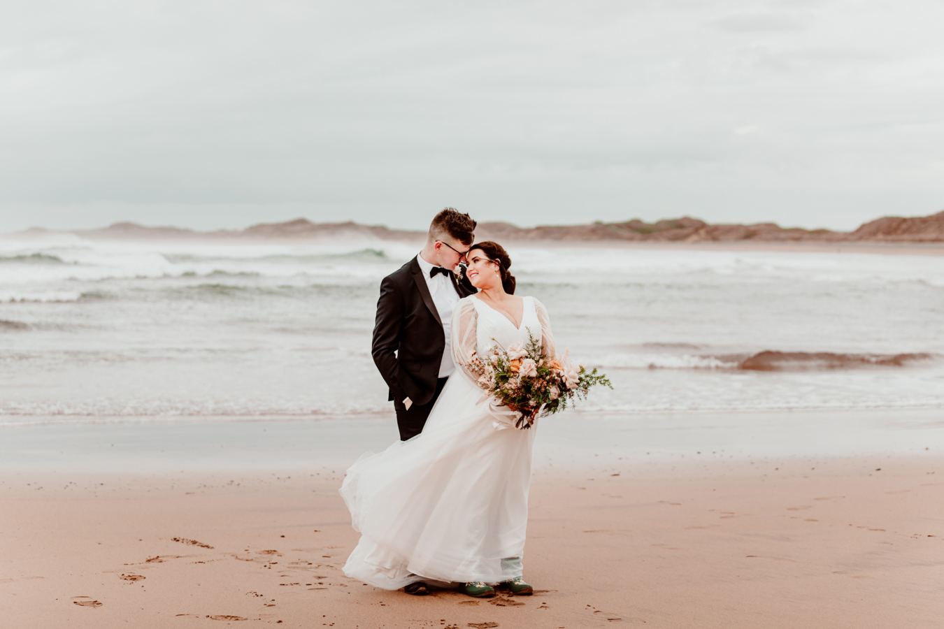 Mariée en robe de mariée ligne A romantique avec manches évêque sur la plage appelée Joanne par Rebecca Ingram