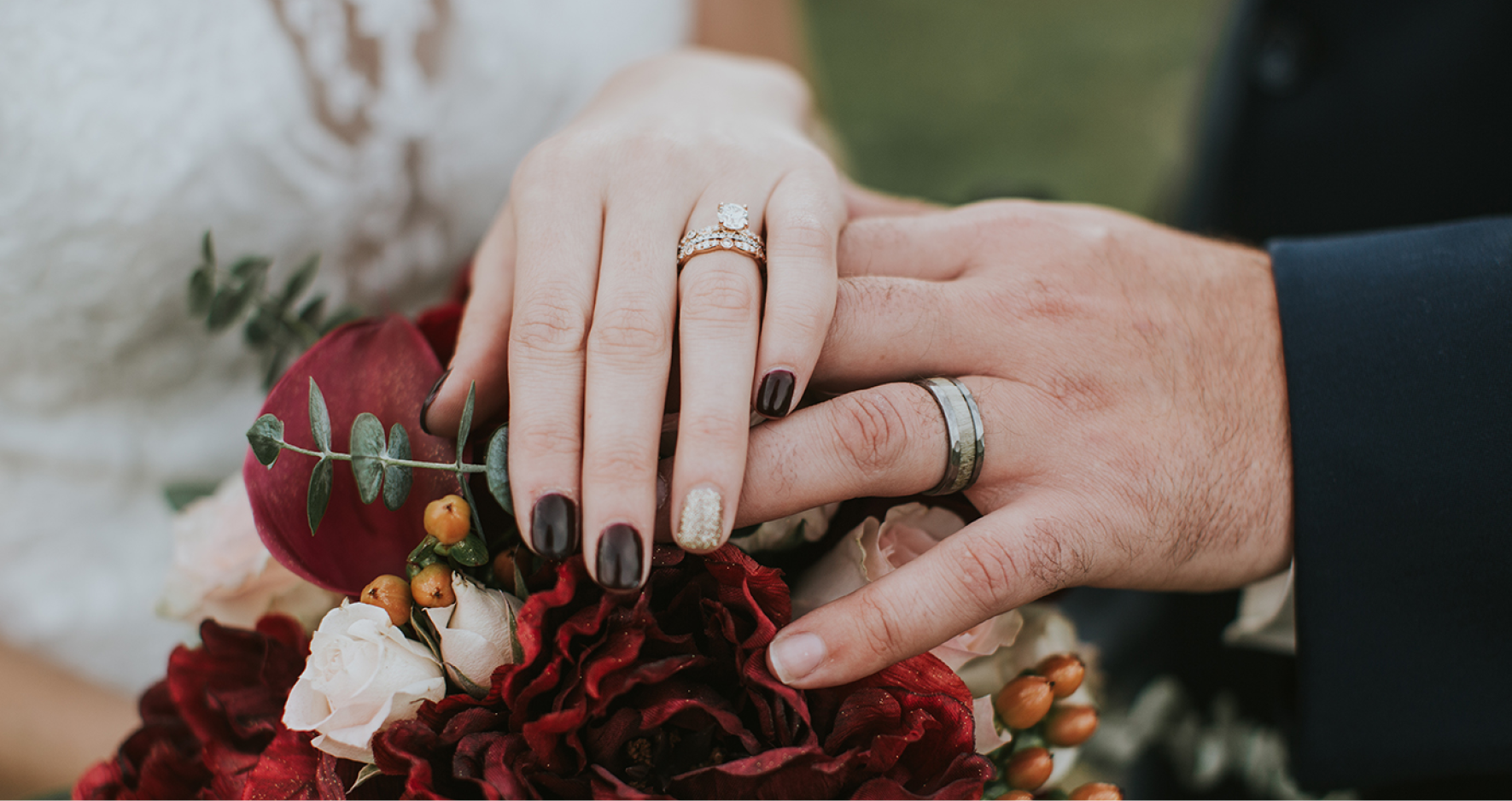 Married Couple Overlapping Hands On Top Of Flower Bouquet Showing Wedding Rings