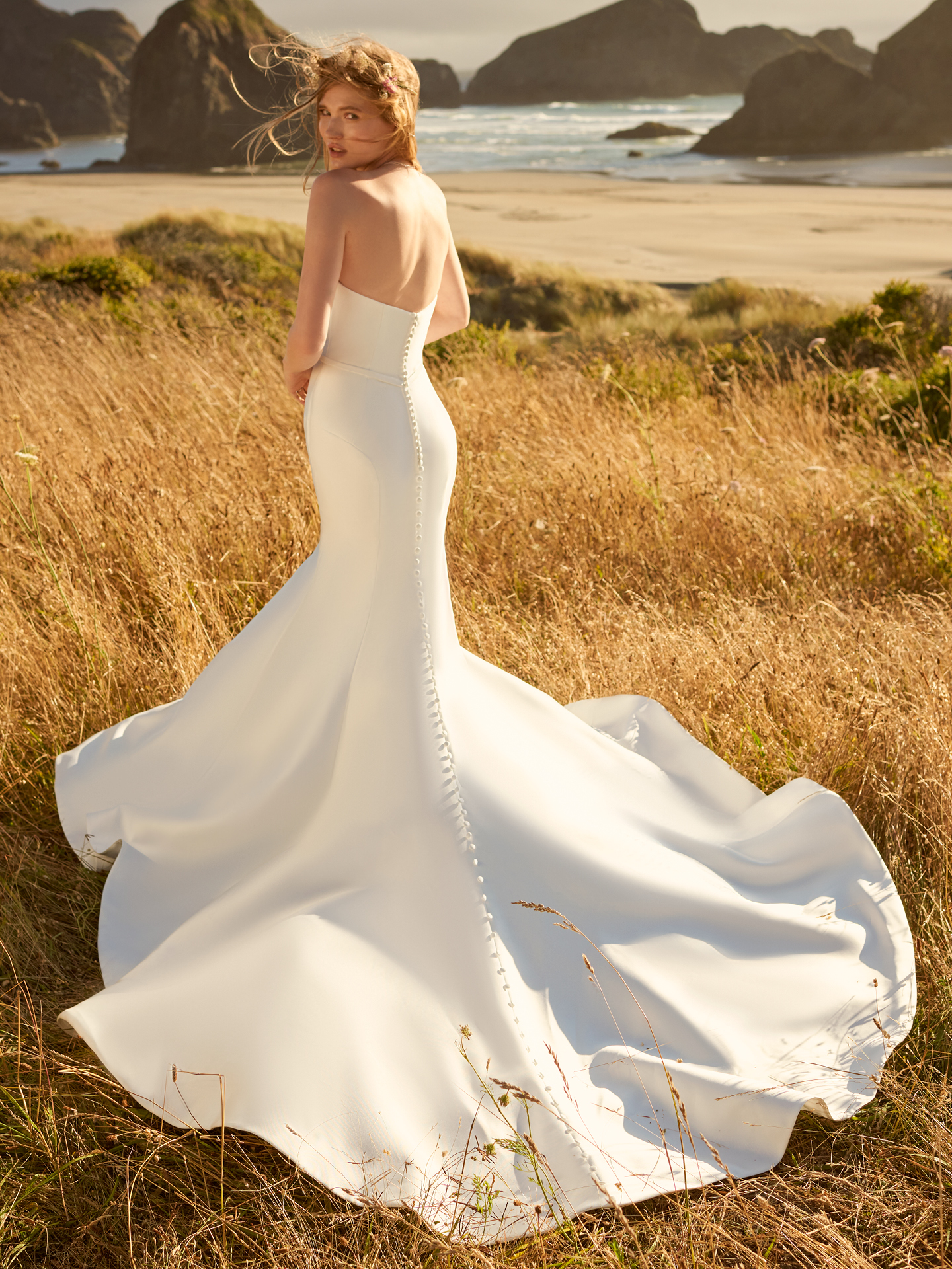 La mariée exhibe le dos de sa robe de mariée appelée Pippa par Rebecca Ingram sur la plage