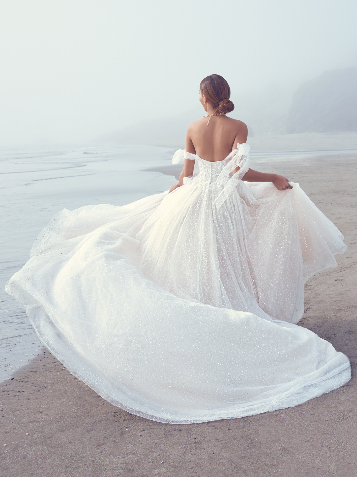 Mariée portant l'une de nos robes de mariée uniques en marchant sur une plage appelée Shasta par Sottero et Midgley