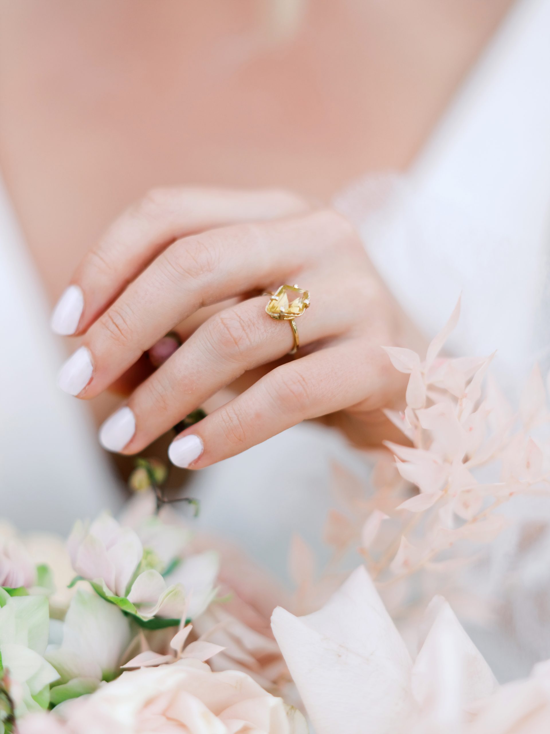Bague de fiançailles sur l'annulaire avec des ongles manucurés et des fleurs
