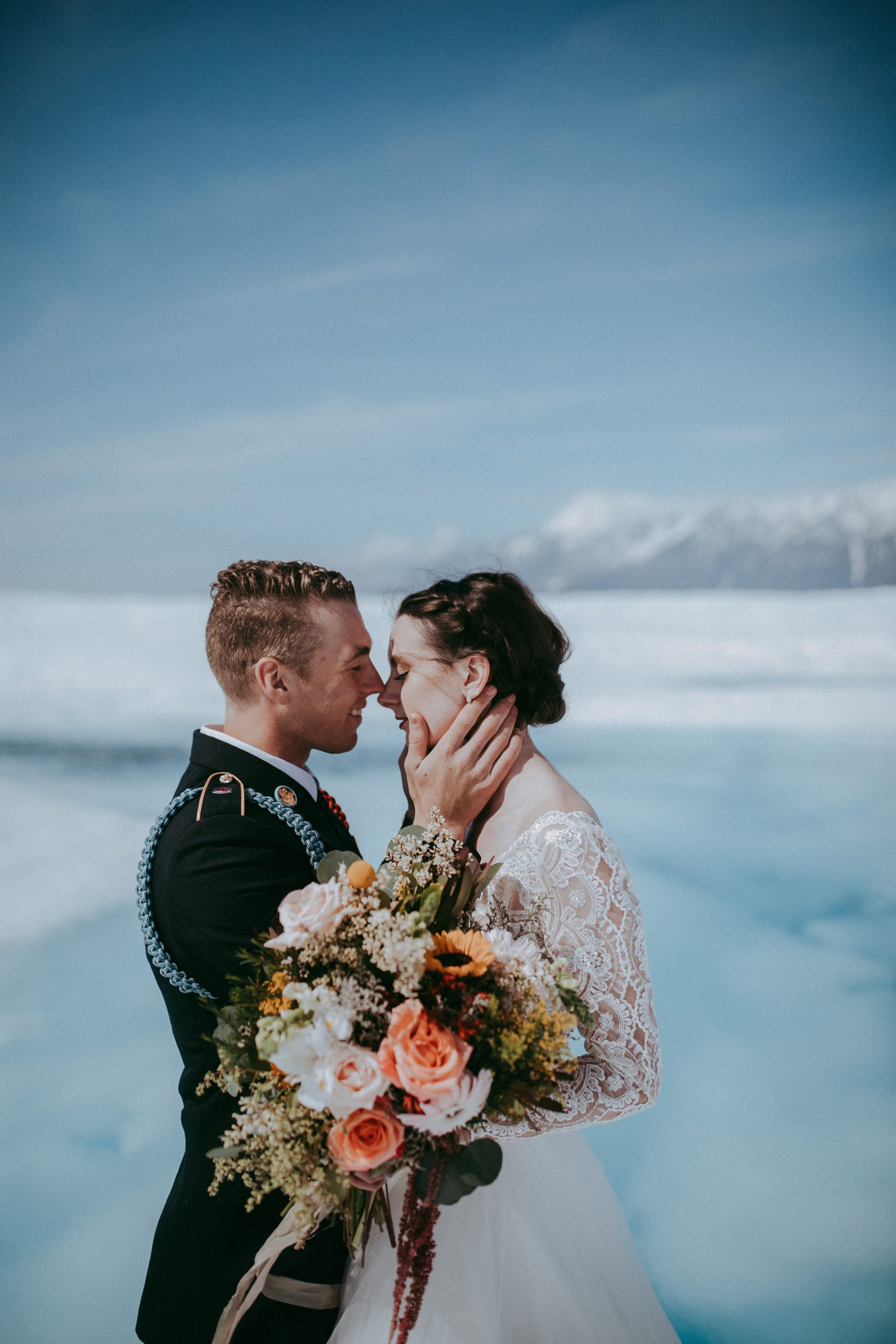 Mariée portant une robe appelée Mallory Dawn par Maggie Sottero se blottissant avec le marié dans Glacier Elopement