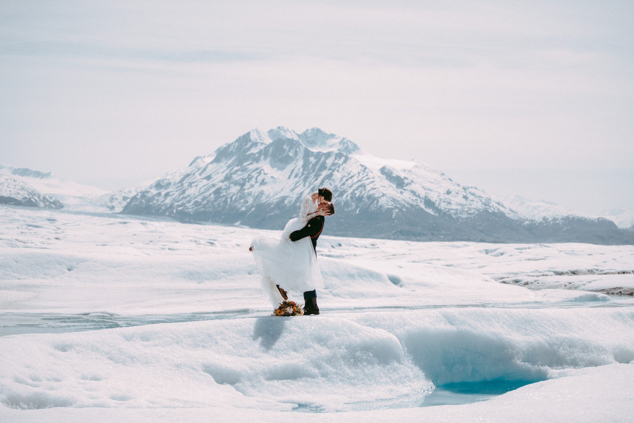 Photographie d'hiver des mariés à Glacier Elopement portant une robe appelée Mallory Dawn par Maggie Sottero