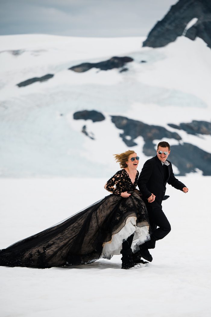 Bride Showing Off Her Dress In The Snow With Groom In A Dress Called Zander By Midgley And Sottero