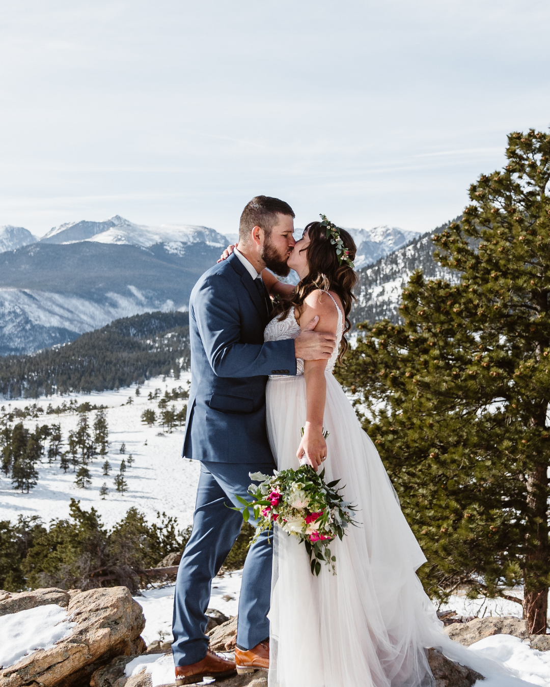 Photographie d'hiver des mariés s'embrassant dans les montagnes pendant l'heure d'or portant une robe appelée Charlene par Maggie Sottero