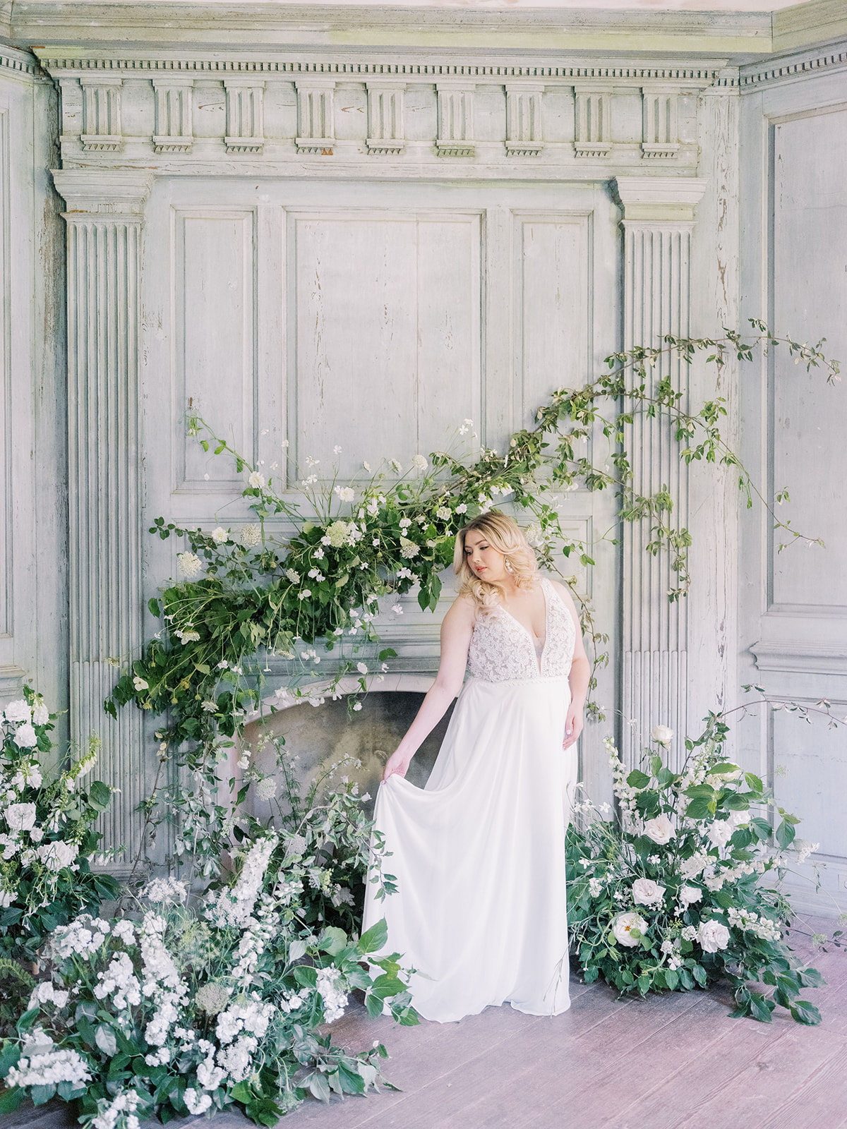 Mariée par des fleurs et une cheminée portant une robe appelée Gabriella par Rebecca Ingram 