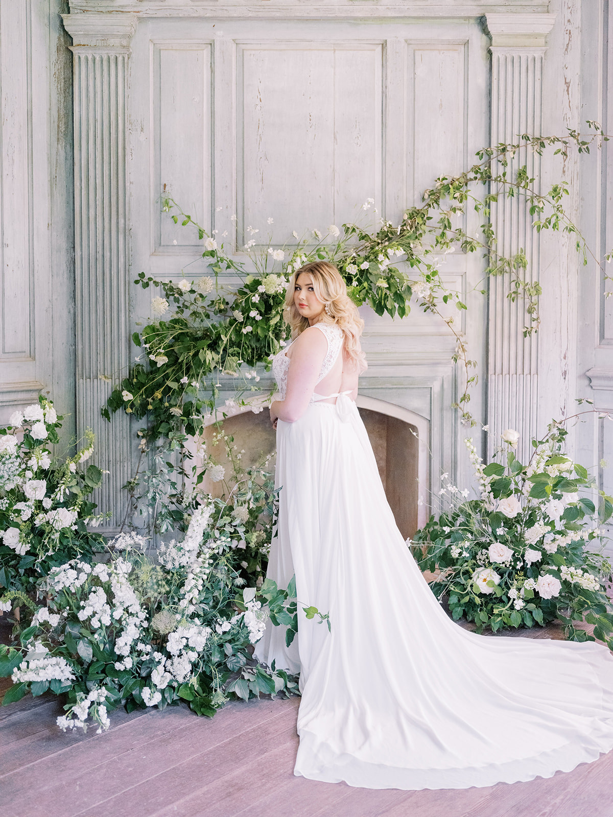 Mariée par des fleurs et une cheminée portant une robe appelée Gabriella par Rebecca Ingram 