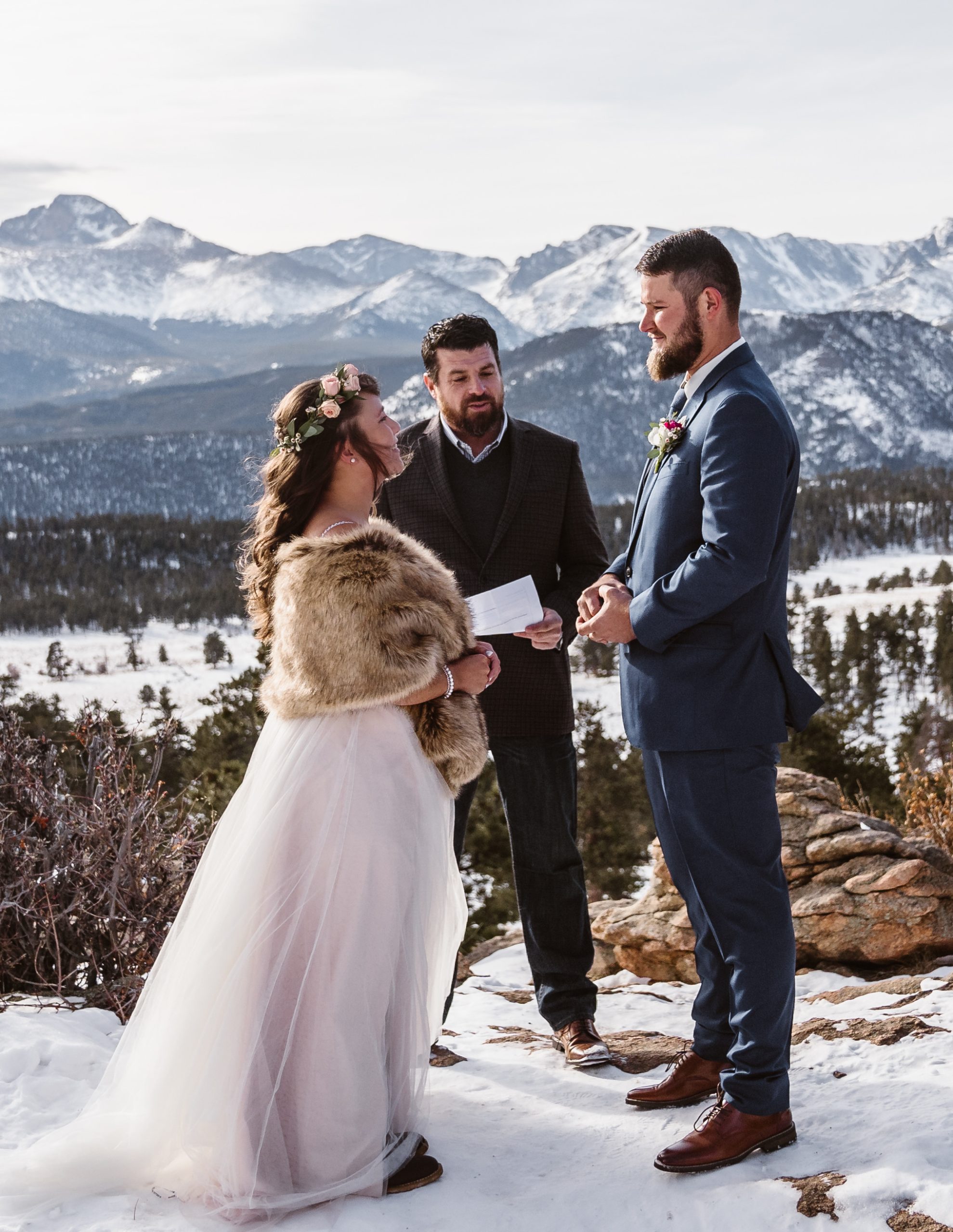 Le marié et la mariée se marient dans un accessoire de manteau de fourrure dans les montagnes dans une robe appelée CHARlene par Maggie Sottero