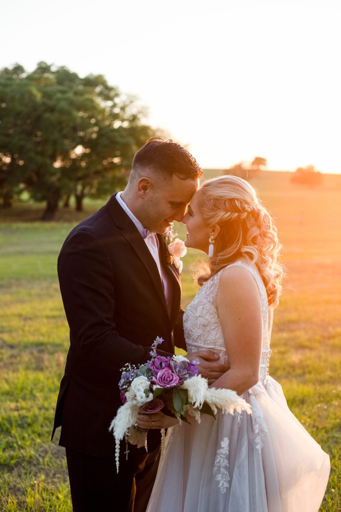 Pantone Color Of The Year 2022 With Bride And Groom Standing In Golden Hour With Bride Wearing A Dress Called Raelynn By Rebecca Ingram