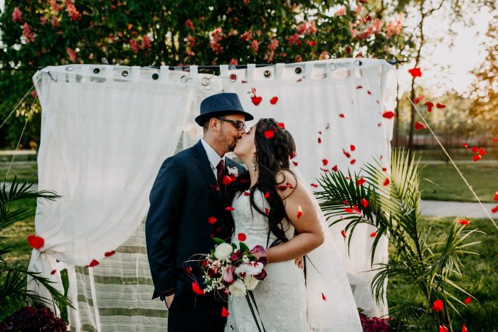 Valentines Day On A Budget Idea Of Bride And Groom Planning Their Wedding With Bride Wearing A Dress Called Brenda By Maggie Sottero With Red Rose Petals Falling