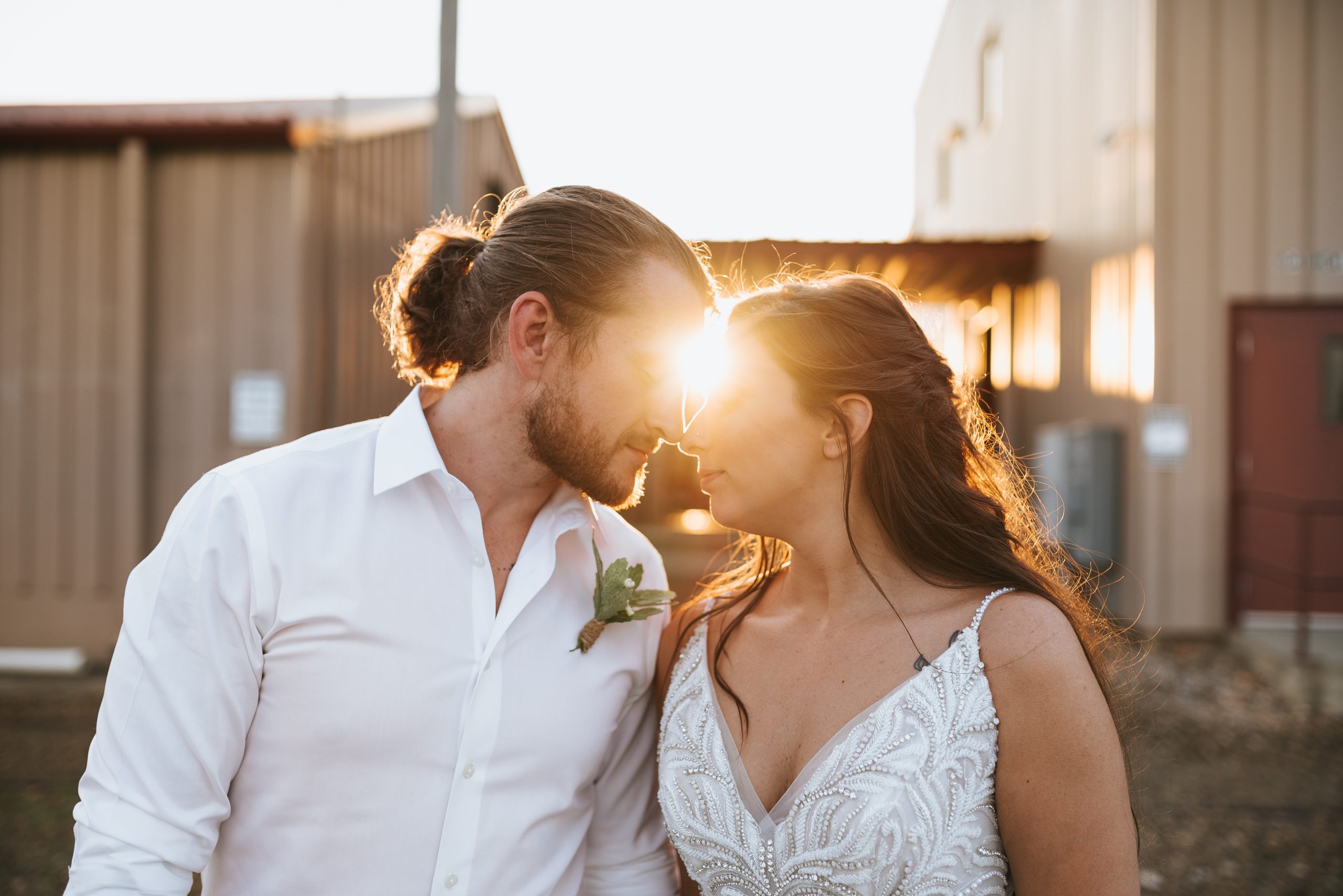 Photographie de la mariée et du marié s'embrassant à l'heure d'or avec la mariée portant une robe appelée Charlene par Maggie Sottero