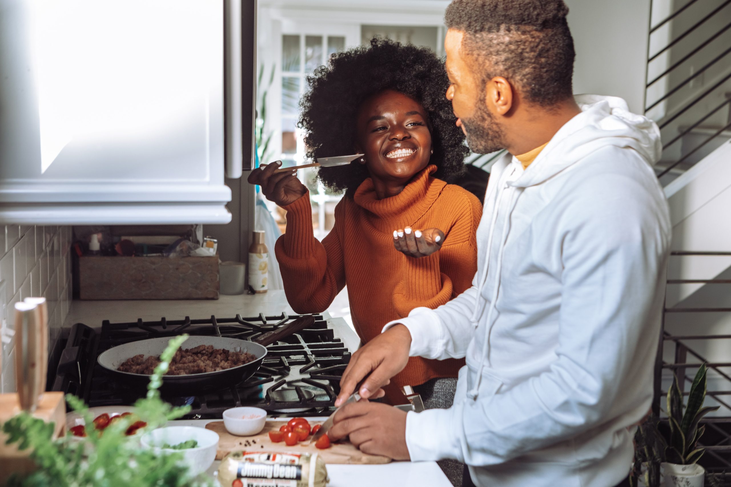 Une femme noire et un homme blanc célèbrent la Saint-Valentin avec un petit budget en cuisinant ensemble un repas romantique