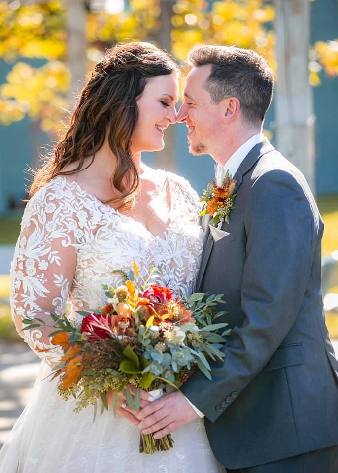 Bride Wearing Long Sleeved Wedding Dress Called Zander By Sottero And Midgley Standing With Her Husband Carrying Autumn Themed Bouquet