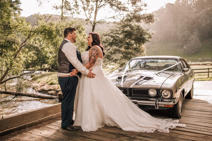 Curvy Brides Wearing A Ball Gown Wedding Dress Called Savannah By Maggie Sottero Standing With Husband Next To Vintage Car