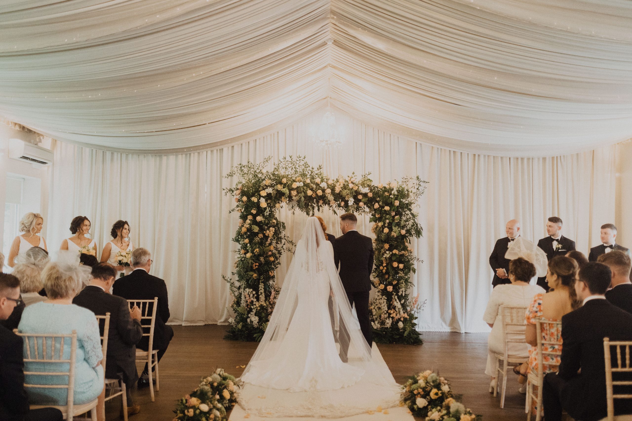   Mariée portant Aston par Sottero et Midgley à la réception de mariage avec son mari dans une tente avec Flower Arch