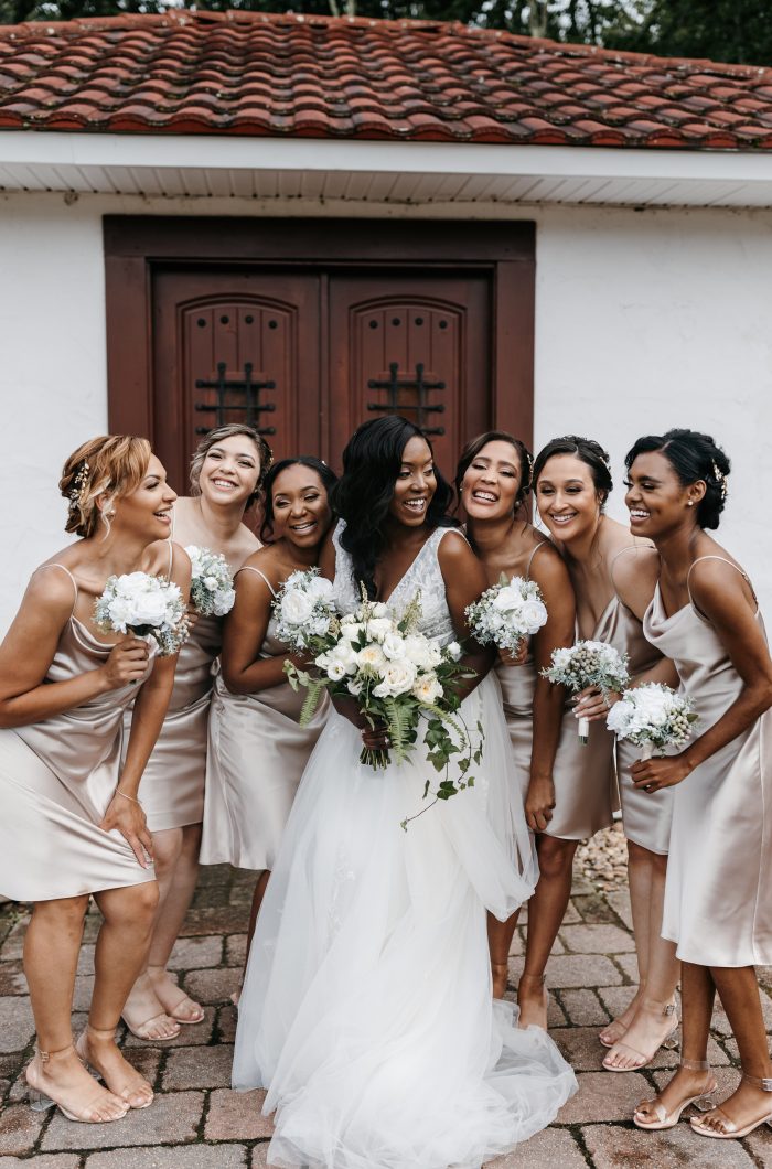 Bride Wearing An Affordable Wedding Dress Called Raelynn By Rebecca Ingram With Bridal Party In Gold And Black