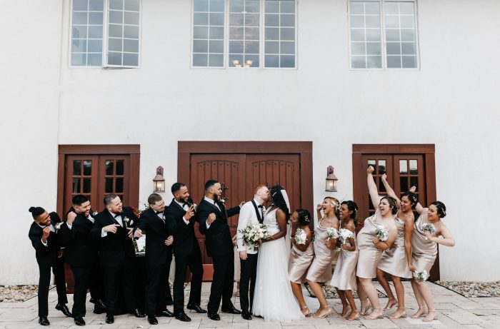 Bride Wearing An Affordable Wedding Dress Called Raelynn By Rebecca Ingram With Bridal Party In Gold And Black