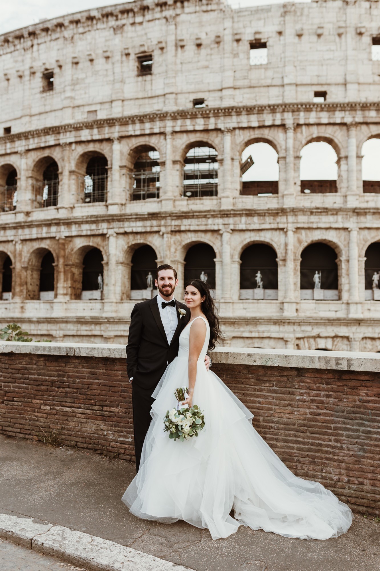 Bride And Groom Standing In Front Of Colleseum With Bride Wearing A Dress Called Fatima By Maggie Sottero