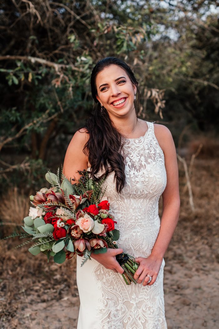 Bride Wearing A Modern High Neck Wedding Gown Called Kevyn By Maggie Sottero Holding A Bouquet With Spring Wedding Colors Of Red And Green 