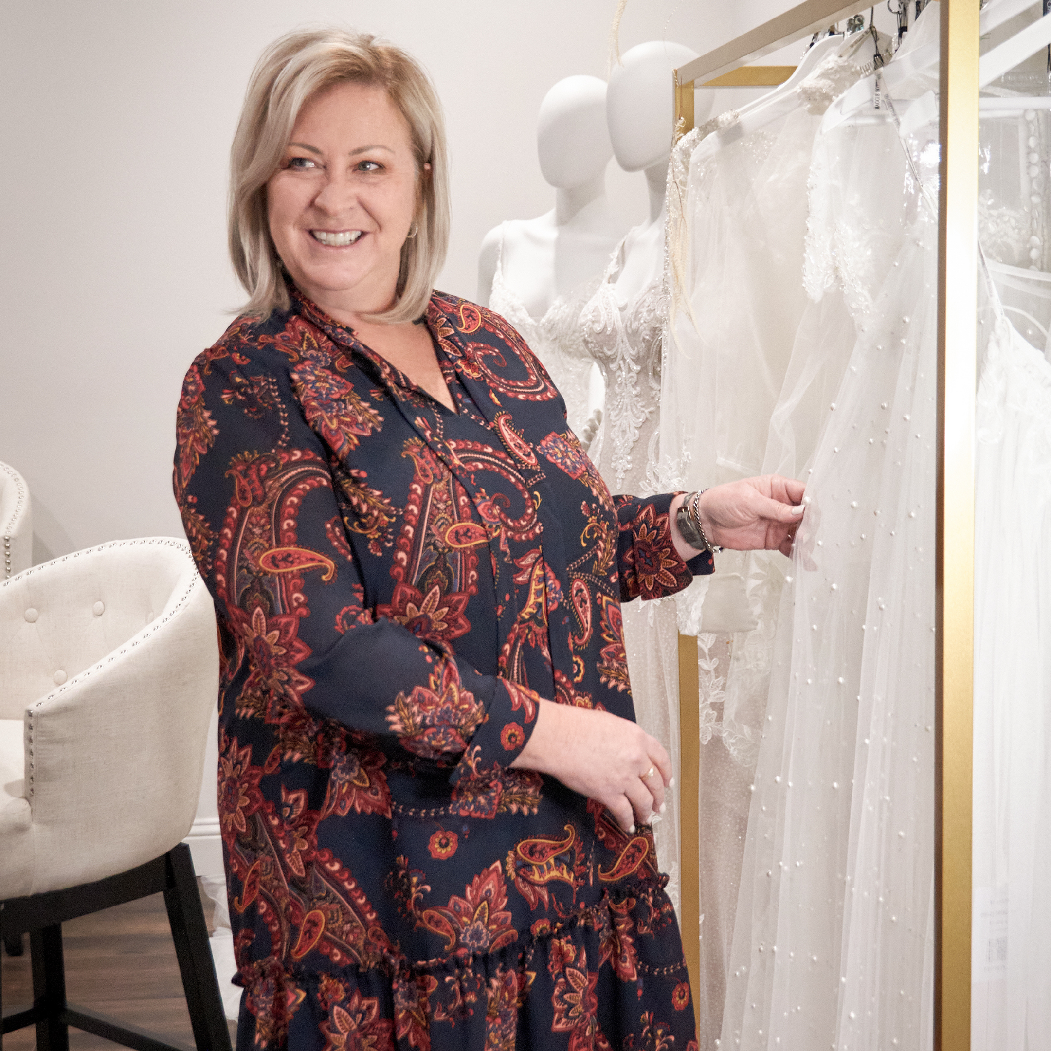 Blog d'entreprises appartenant à des femmes En-tête de Maggie Sottero PDG Kelly Midgley devant les robes de mariée de Maggie Sottero